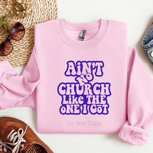 Pink sweatshirt with purple text on a white surface with accessories around