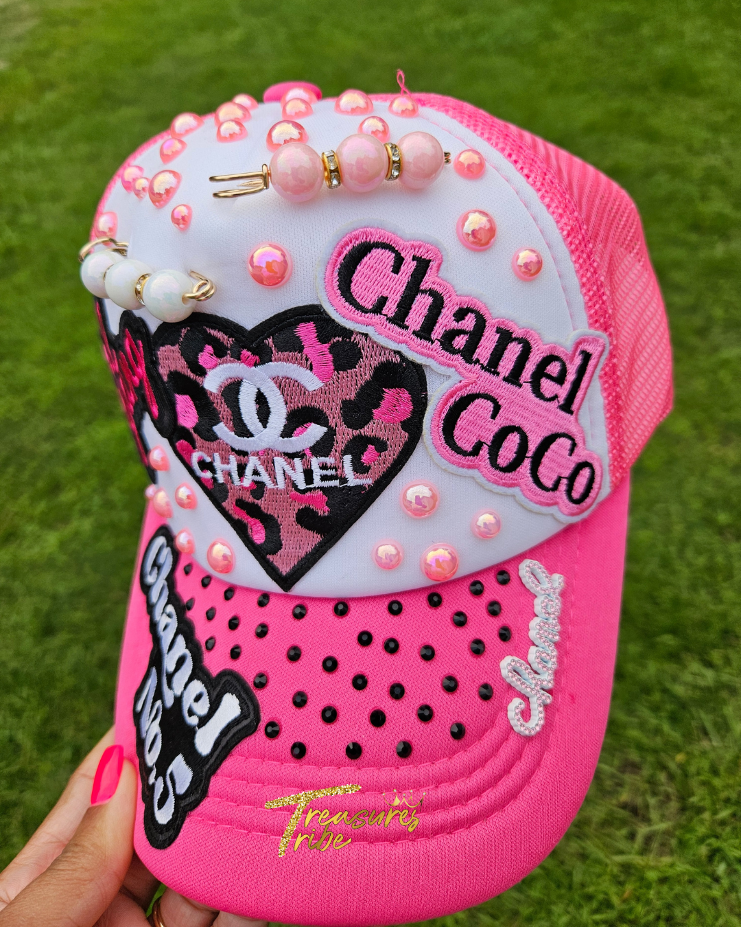 Pink cap with Cha*el elements and decorative elements on a grass background
