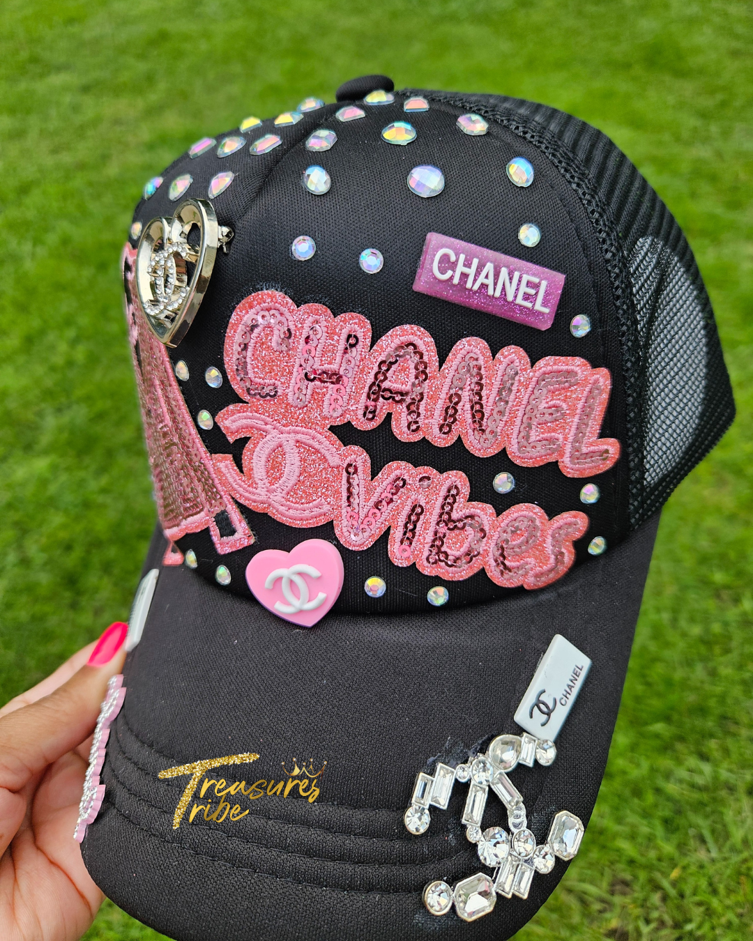Black Cha*el cap with pink text and embellishments on a grass background