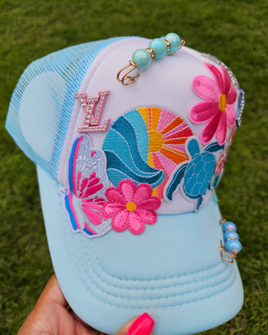 Colorful embroidered cap with floral and butterfly designs on a grass background