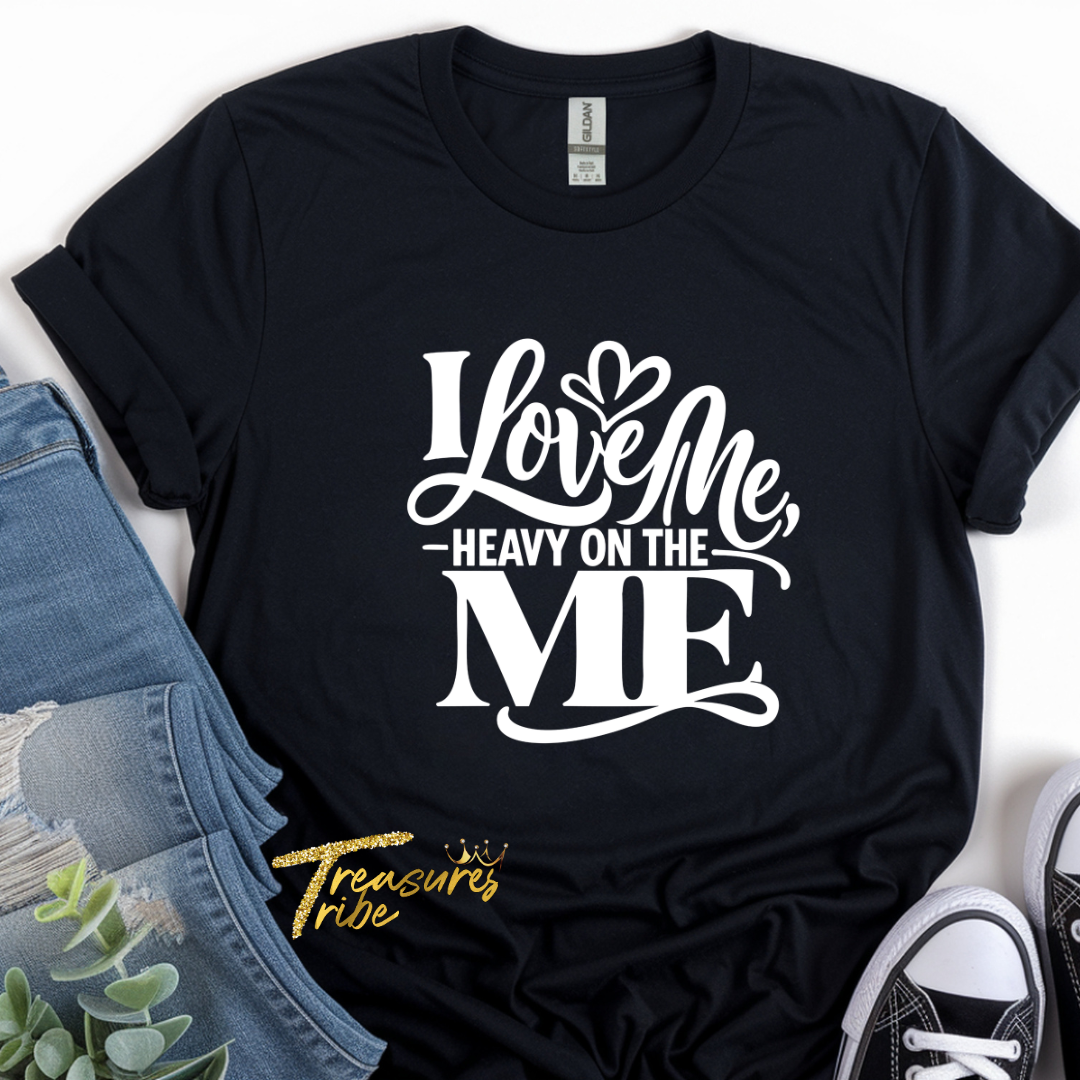 Black t-shirt with 'I Love Me, Heavy on the ME' text design, placed on a white surface with jeans and sneakers.