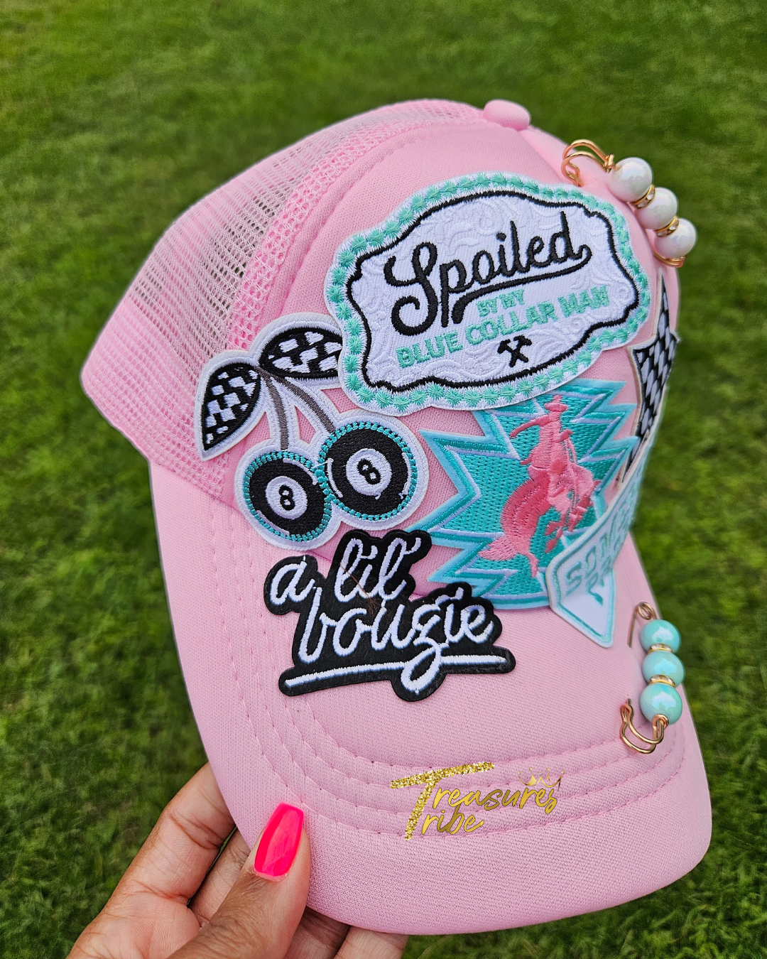 Pink cap with decorative patches and beads on a grass background