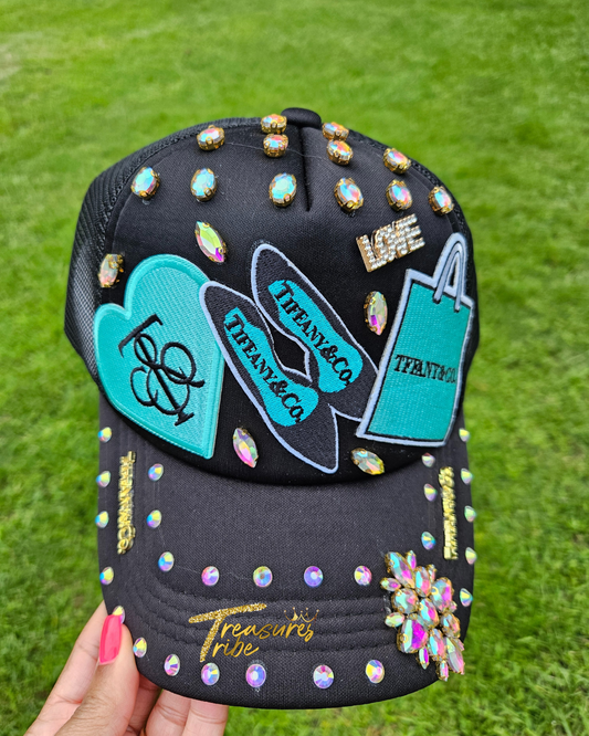 Decorative black cap with colorful embellishments held against a grass background