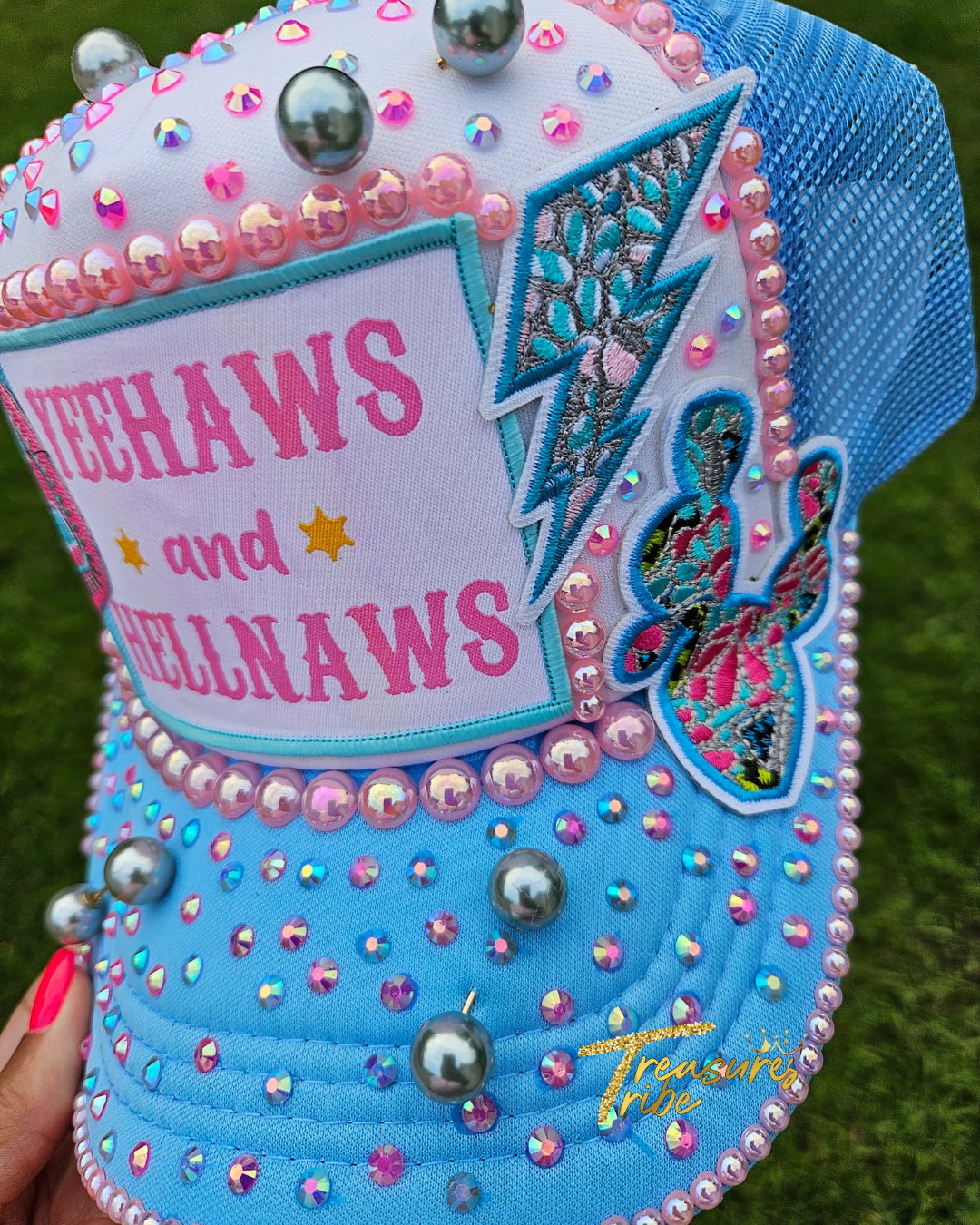 Decorative hat with 'YeeHaws and Hellnaws' text and embellishments on a grass background