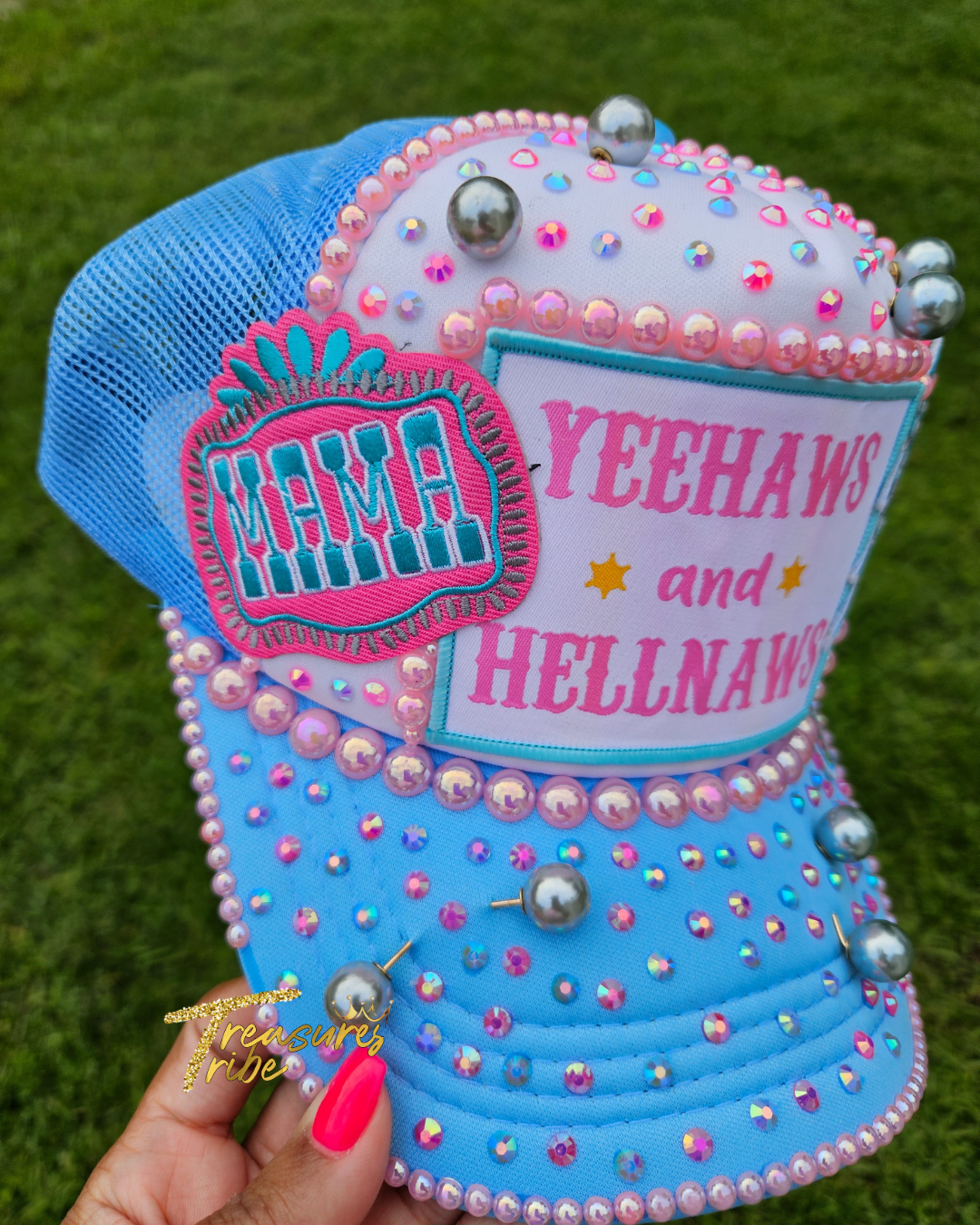 Decorative blue hat with 'Mama Yeehaws and Hellnaws' text and embellishments on a grass background.